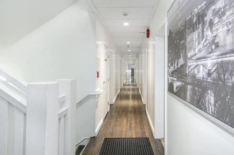 A long hallway with a black and white picture on the wall.